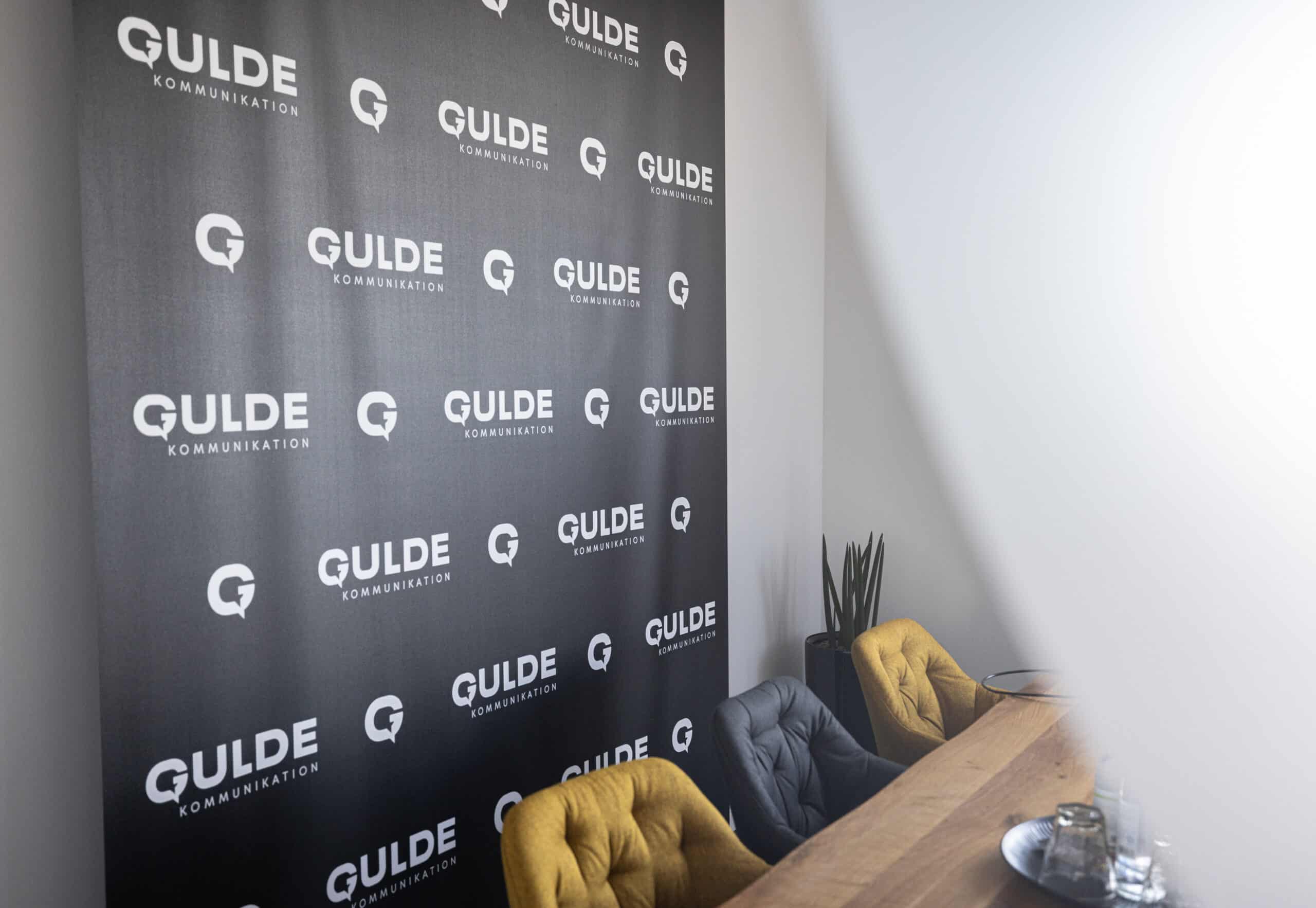 Werbeagentur Hechingen - Sitze vor Gulde Wand mit Logos